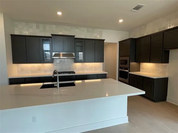 a large kitchen with stainless steel appliances a large counter top