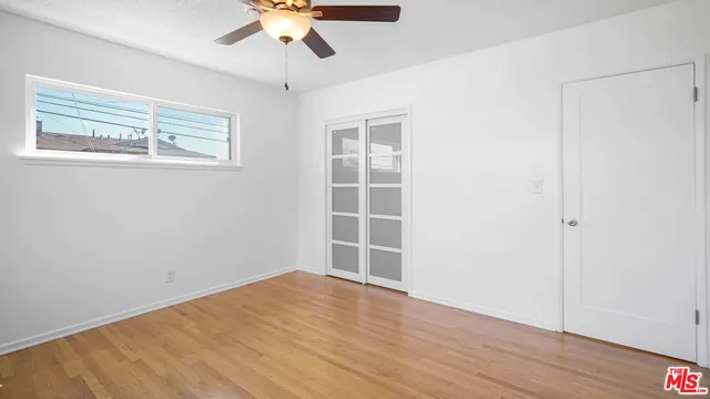 a view of empty room with wooden floor and fan