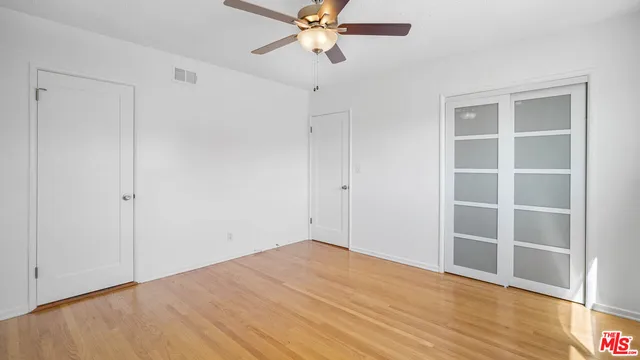 a view of empty room with wooden floor and fan