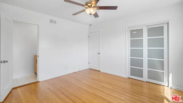 a view of empty room with wooden floor and fan