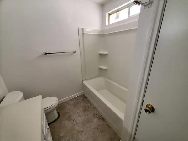 a bathroom with a granite countertop toilet and a tub