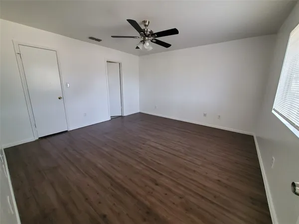 an empty room with wooden floor and ceiling fan