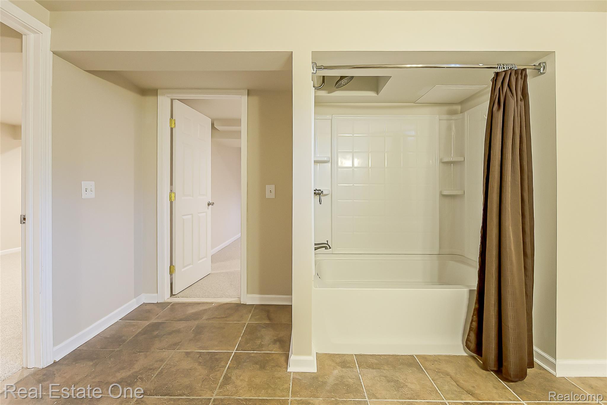1013 Rochelle Park Drive Rochester, MI 48307 - Photo 53 of 74 Tile flooring, white bathtub with integrated shower, wall-mounted showerhead, and white subway tile-patterned shower surround