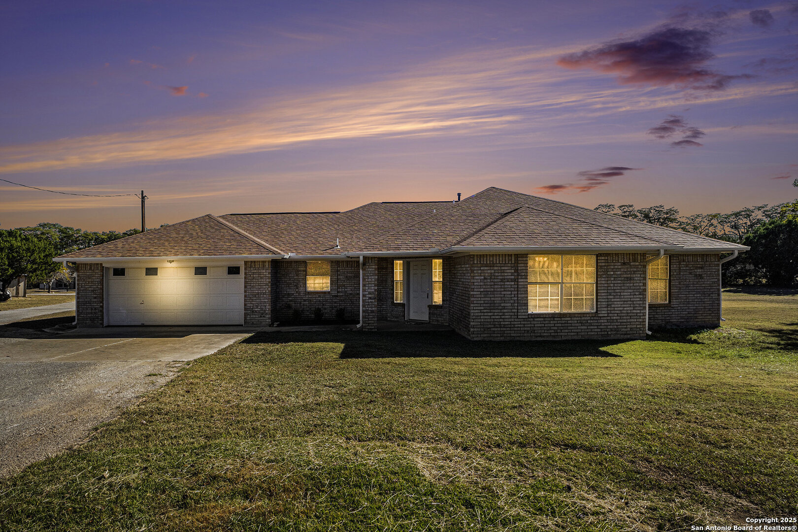a front view of house with yard and trees in the background