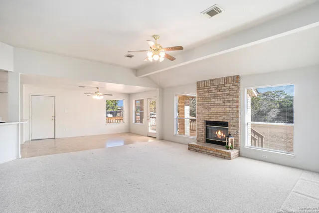 an empty room with windows and fireplace