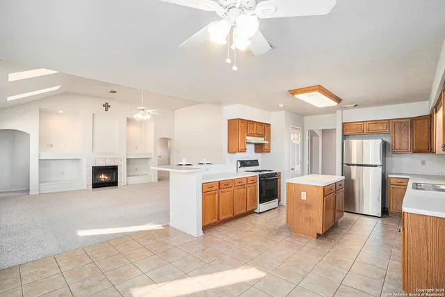 a large white kitchen with a window and refrigerator