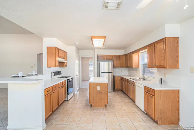 a large kitchen with a stove a sink dishwasher and a refrigerator