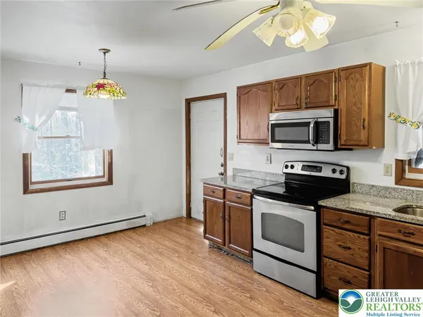 a kitchen with stainless steel appliances granite countertop a stove top oven a sink dishwasher a dining table and chairs with wooden floor