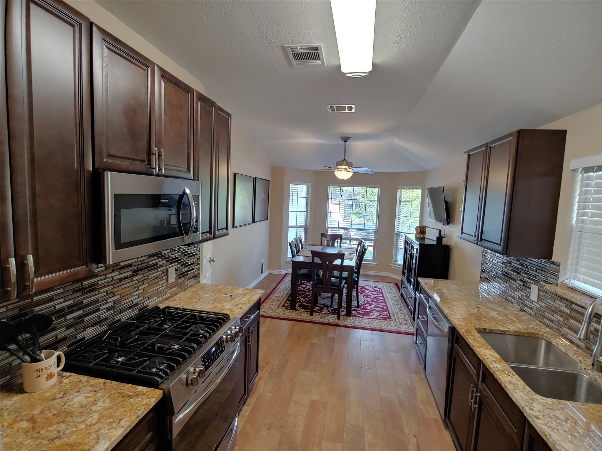 8124 Tockington Way Austin, TX 78748 - Photo 5 of 28 a kitchen with stainless steel appliances granite countertop a stove top oven a sink dishwasher a dining table and chairs with wooden floor