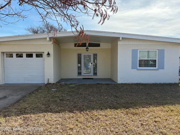a view of a grey house with a large tree