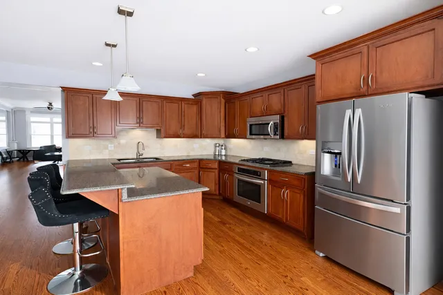 a kitchen with kitchen island granite countertop stainless steel appliances and wooden cabinets
