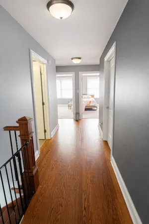 a view of a hallway to a livingroom with wooden floor and furniture