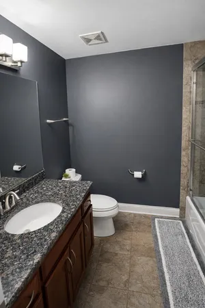 a bathroom with a granite countertop sink toilet and shower
