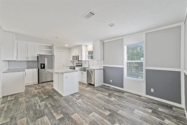 a room with kitchen island a sink wooden floor and view living room