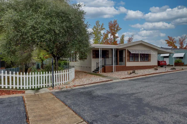 a front view of a house with a garden and trees