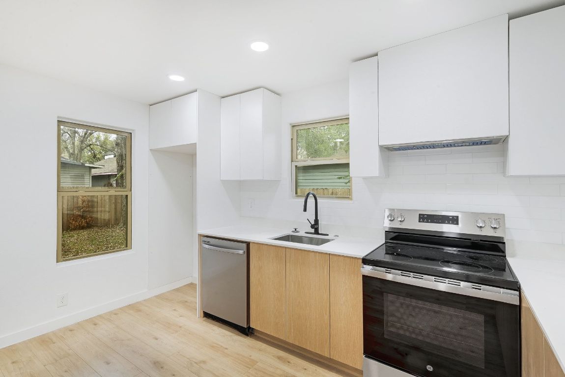 2404 Santa Rita Street Austin, TX 78702 - Photo 11 of 27 Kitchen featuring modern cabinets, appliances with stainless steel finishes, light wood finished floors, white cabinets, and recessed lighting