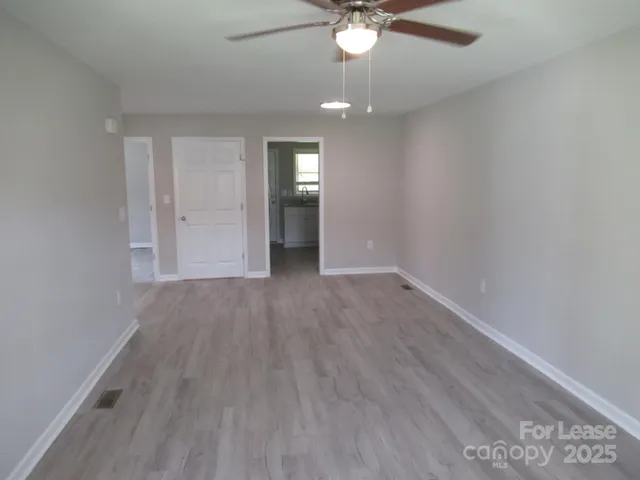an empty room with wooden floor and a ceiling fan