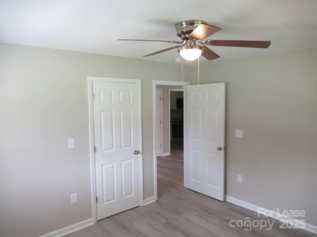an empty room with wooden floor and fan