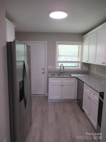 a kitchen with a sink cabinets stainless steel appliances and a window