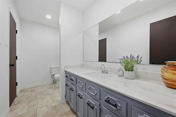 a bathroom with a granite countertop sink a toilet and a large mirror