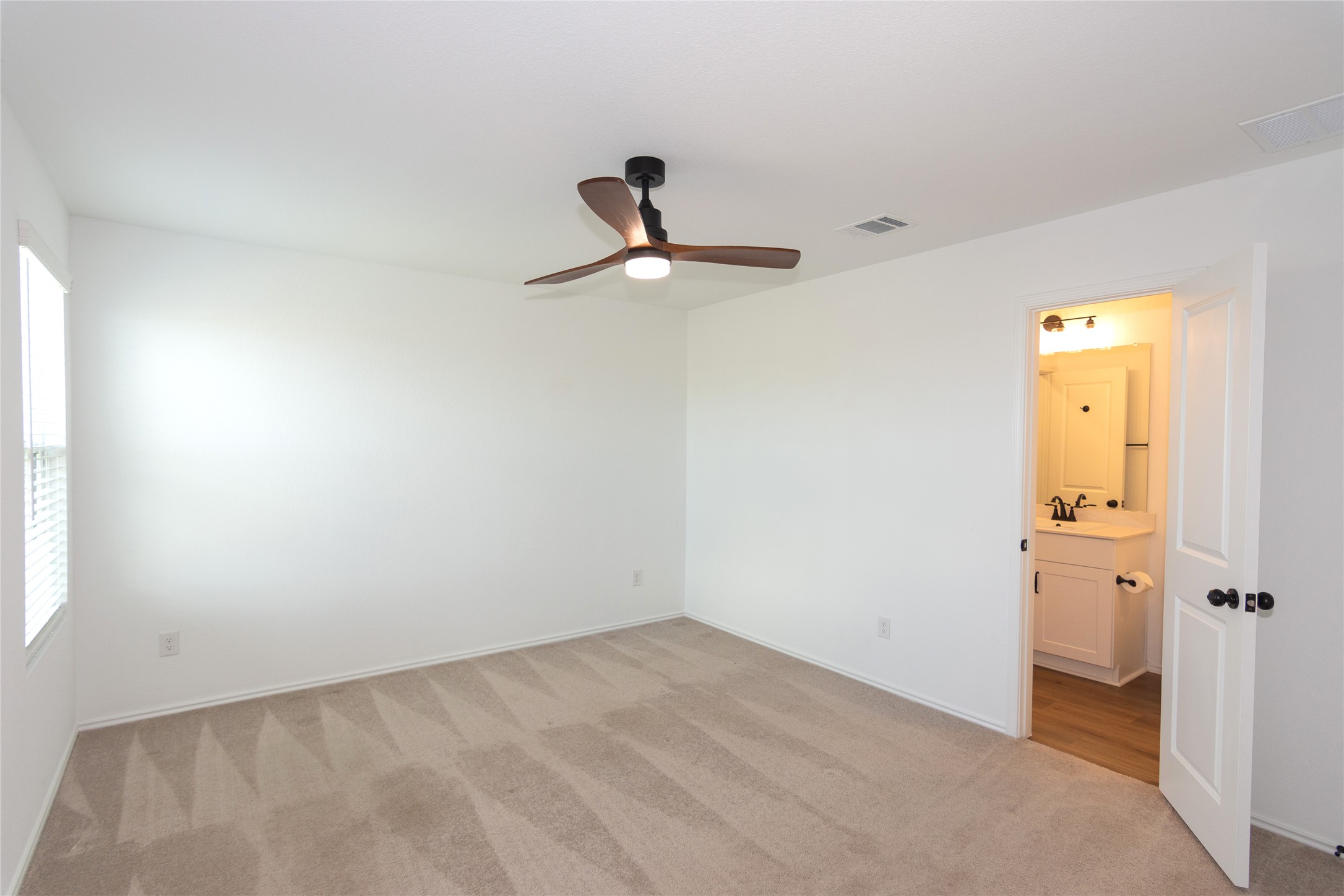 548 Rancho Del Cielo Loop Jarrell, TX 76537 - Photo 15 of 40 Spacious primary bedroom featuring neutral carpeting, a ceiling fan with integrated lighting, and a window with horizontal blinds