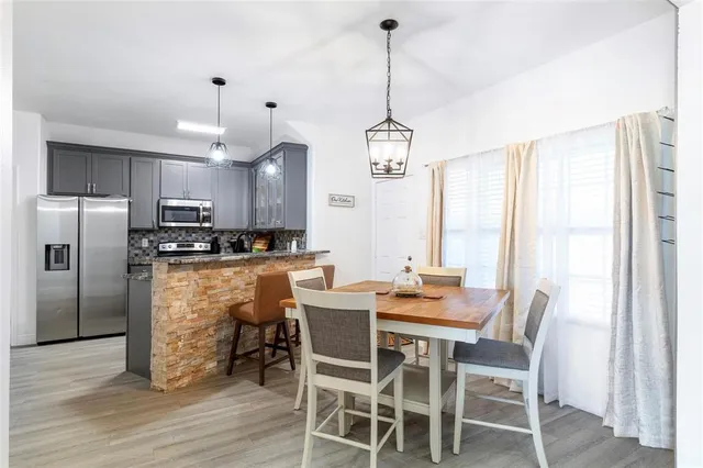 a view of a dining room and livingroom with furniture wooden floor a chandelier