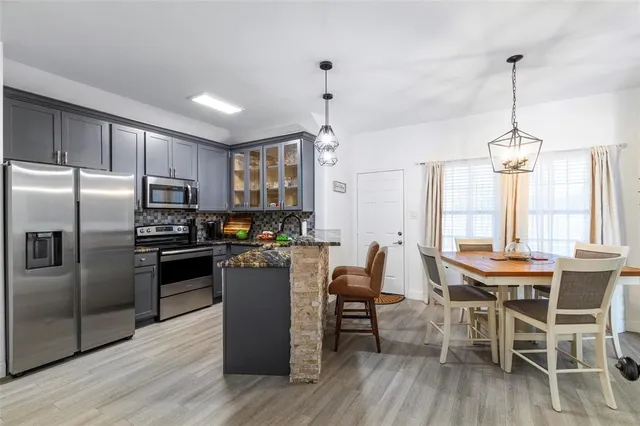a kitchen with stainless steel appliances granite countertop a table chairs stove and refrigerator