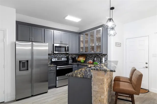 a kitchen with stainless steel appliances granite countertop a refrigerator a stove a sink dishwasher a dining table and chairs with wooden floor