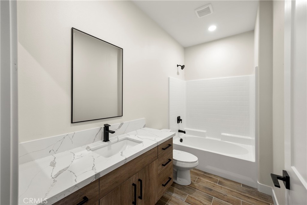 22324 Rancho Street Apple Valley, CA 92308 - Photo 34 of 47 a bathroom with a granite countertop sink toilet a large mirror a bathtub and shower