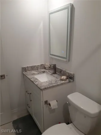 a bathroom with a granite countertop toilet sink and mirror