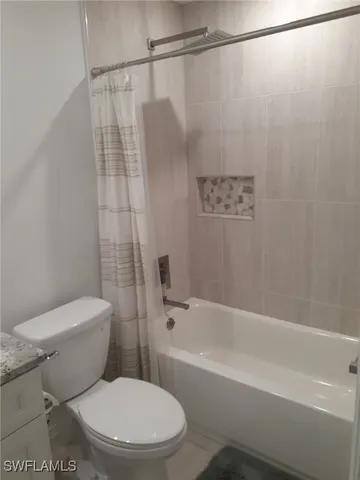 a white toilet sitting next to a bath tub and a shower