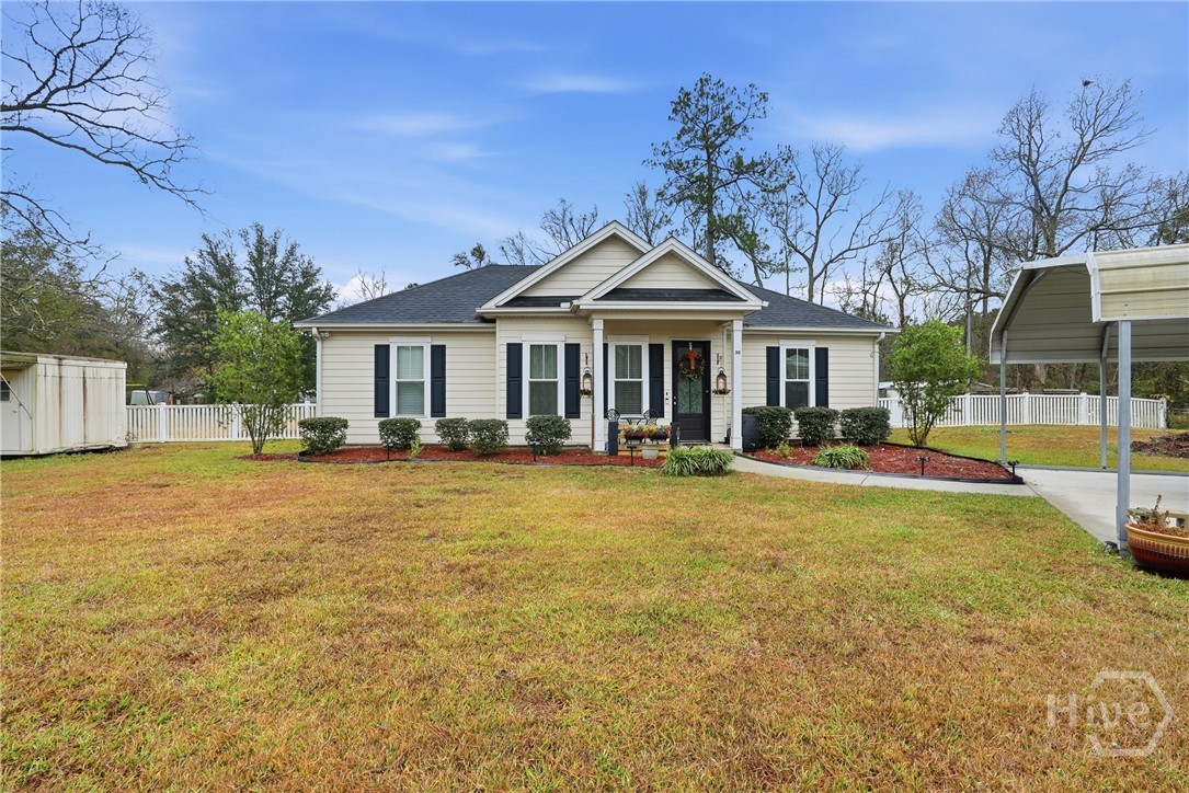 Charming single-story beige suburban home with black shutters, front porch, manicured lawn, shrubs, and detached carport in a peaceful residential neighborhood.
