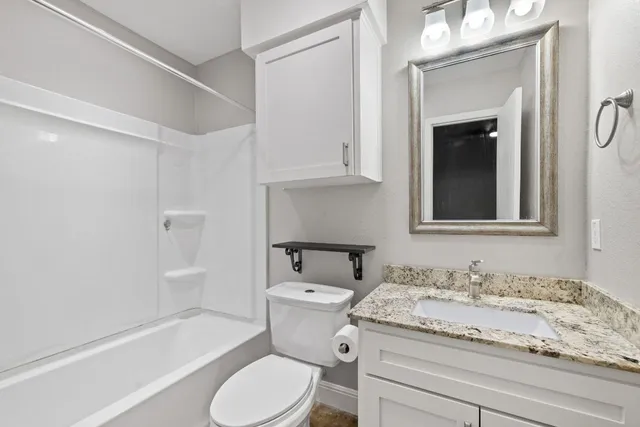 a bathroom with a granite countertop toilet sink and mirror