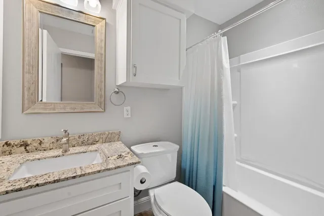 a bathroom with a granite countertop sink a toilet and a mirror