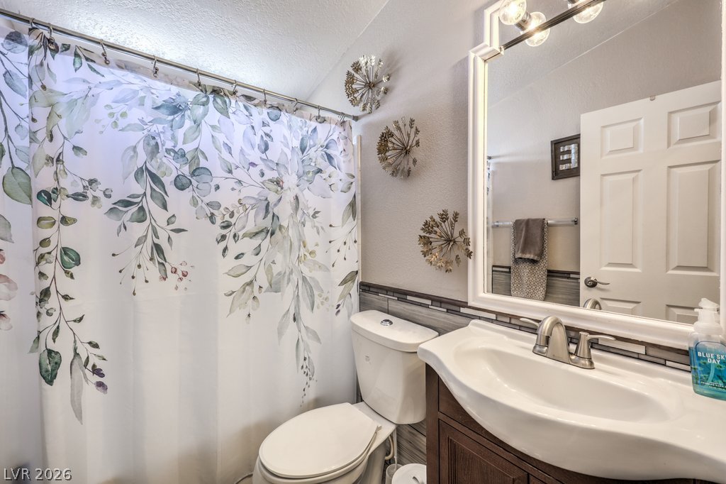 4375 Pinwheel Street Logandale, NV 89021 - Photo 29 of 52 A well-appointed bath with a decorative shower curtain and a bright, reflective vanity mirror.