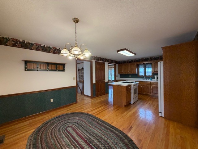 5897 Country Meadow Lane Clinton, IL 61727 - Photo 14 of 59 a kitchen with kitchen island a stove a refrigerator a oven a dining table and chairs with wooden floor