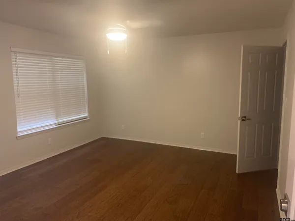 an empty room with wooden floor and windows in it