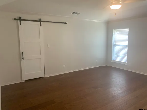 an empty room with wooden floor closet and windows