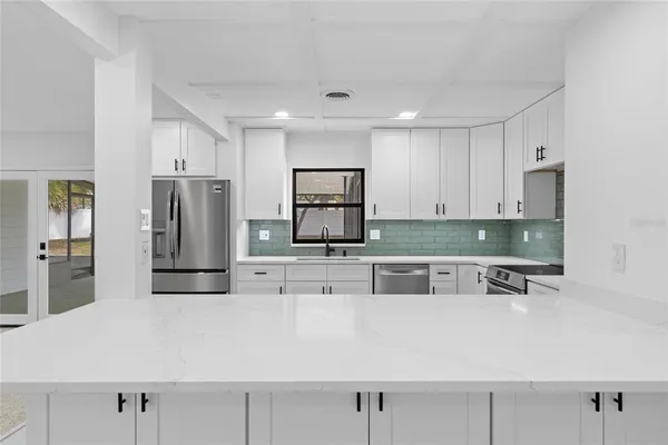 a kitchen with stainless steel appliances granite countertop a sink and a refrigerator