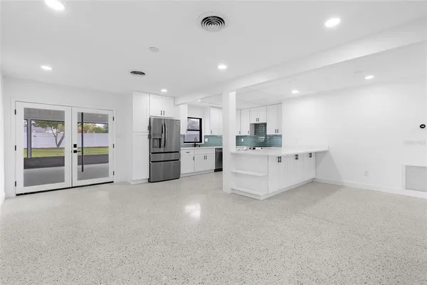 a large white kitchen with stainless steel appliances kitchen island a large counter top and a refrigerator