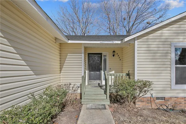 an empty room with wooden floor chandelier fan and windows