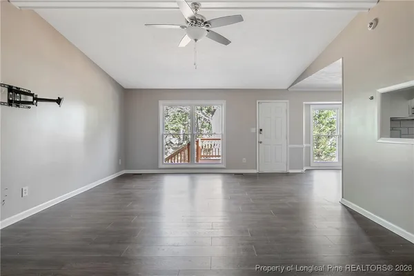 a view of an empty room with a window and wooden floor