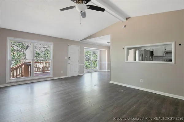 a view of an empty room with wooden floor fireplace and a window