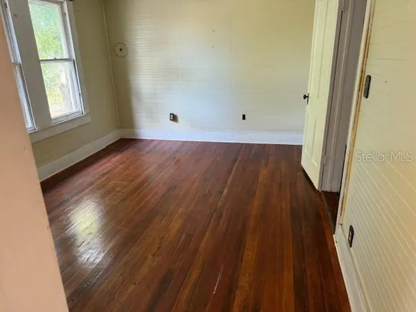 an empty room with wooden floor and windows