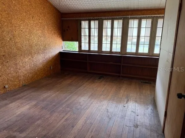 an empty room with wooden floor and windows