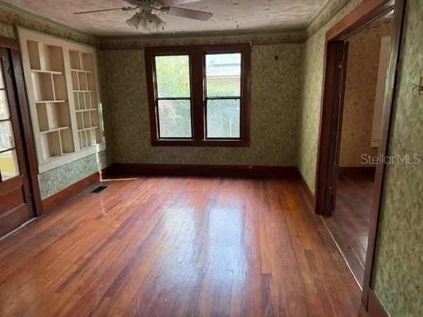 a view of an empty room with wooden floor and a window