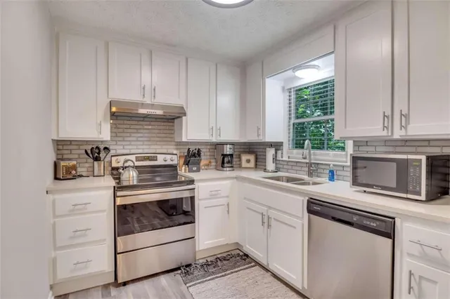 a kitchen with white cabinets and appliances