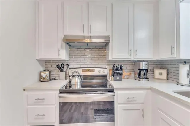a kitchen with a stove and white cabinets