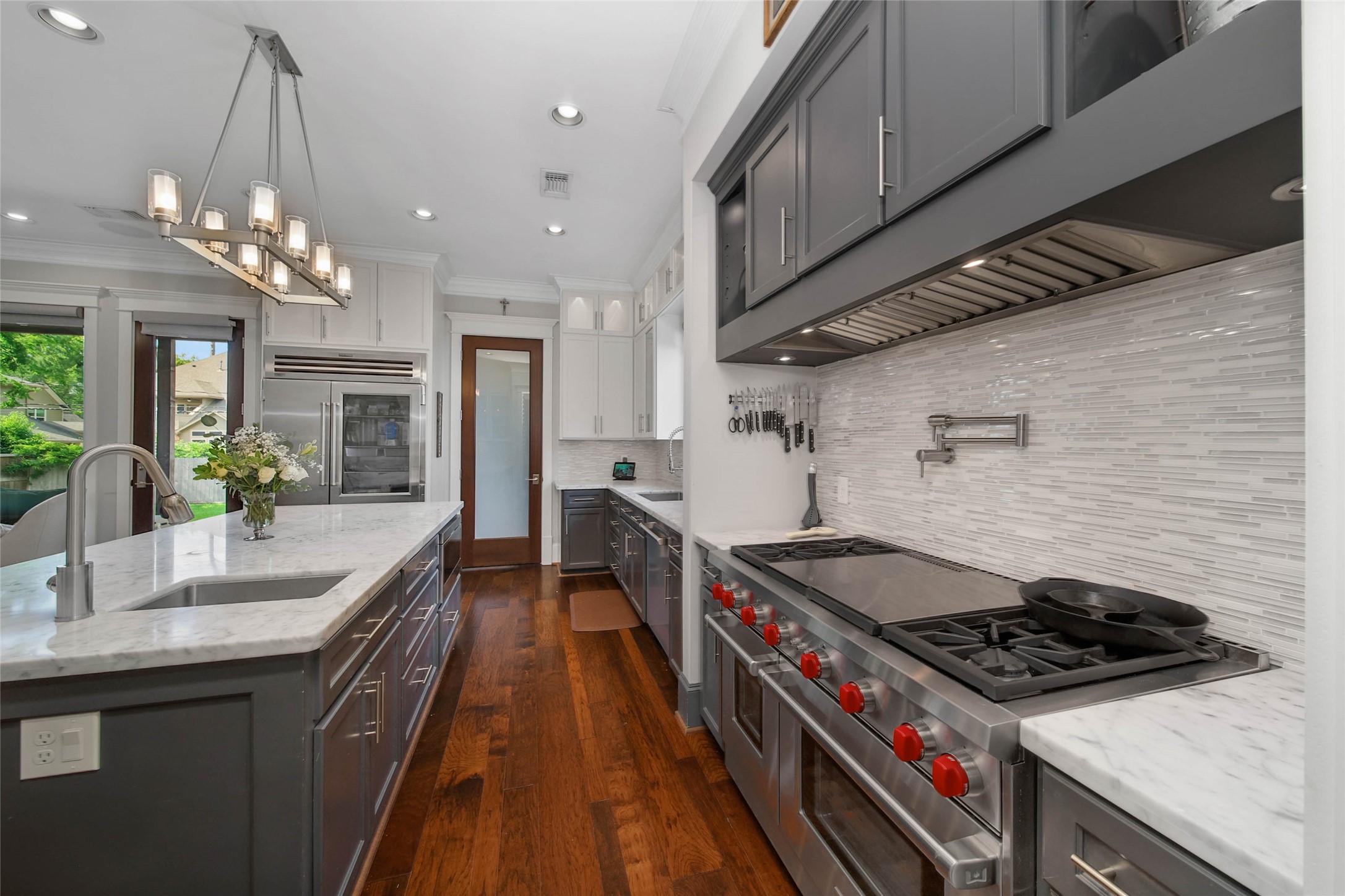 416 West 33rd Street Houston, TX 77018 - Photo 12 of 47 Designed for the culinary enthusiast, this luxury kitchen showcases a professional-grade Wolf gas range with built-in griddle, convenient pot filler, expansive marble countertops and an oversized island with prep sink. A secondary sink, custom cabinetry, designer vent hood and premium stainless refrigeration complete this thoughtfully curated space blending functionality with elevated style.