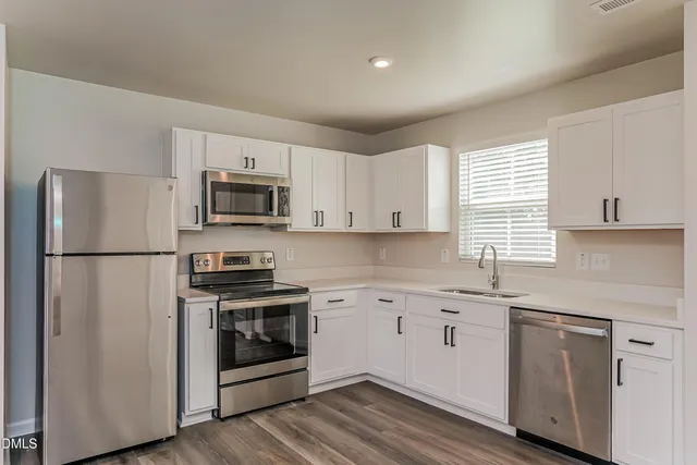 a kitchen with a sink a microwave a refrigerator and cabinets